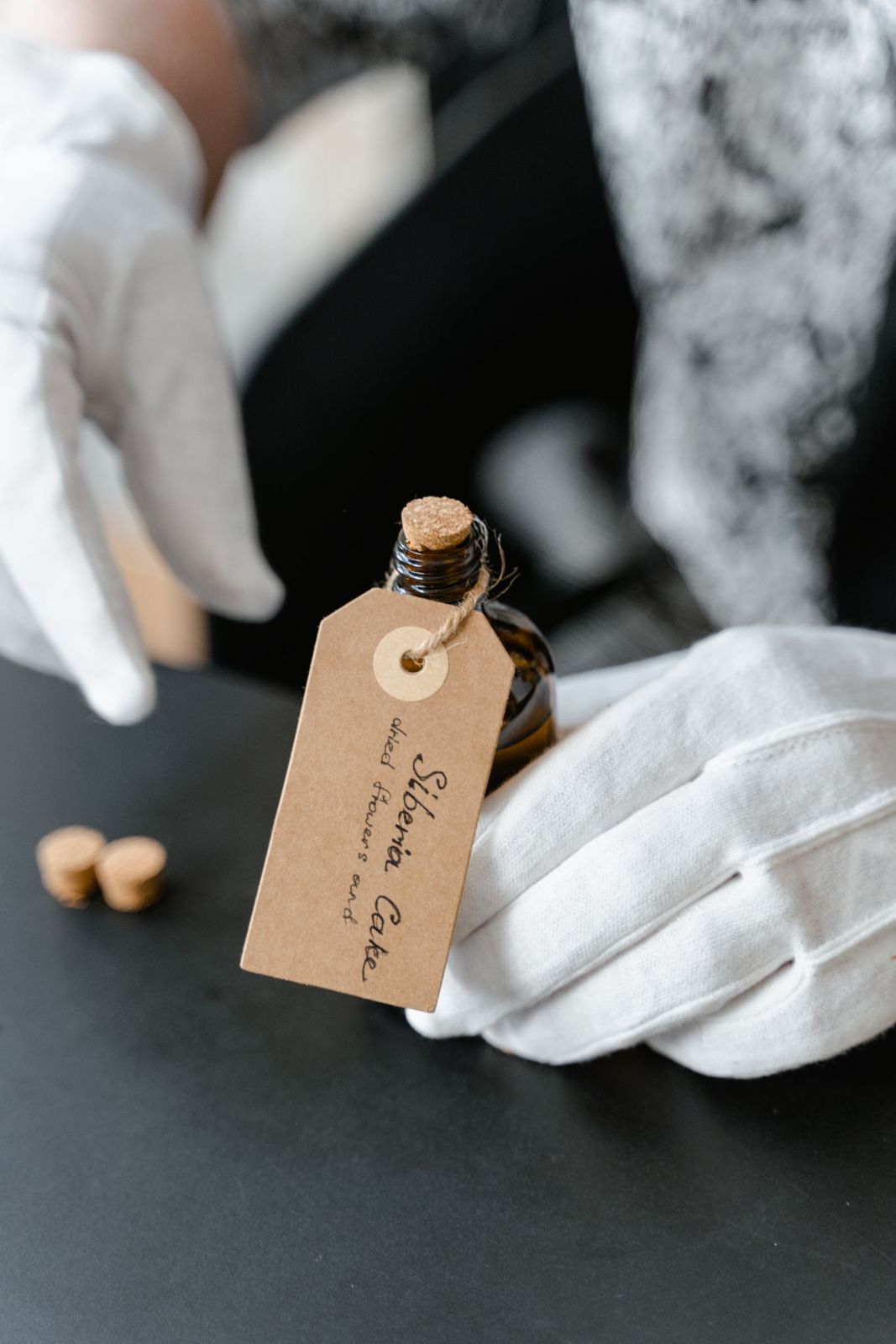 Gloved hands labelling amber perfume bottles